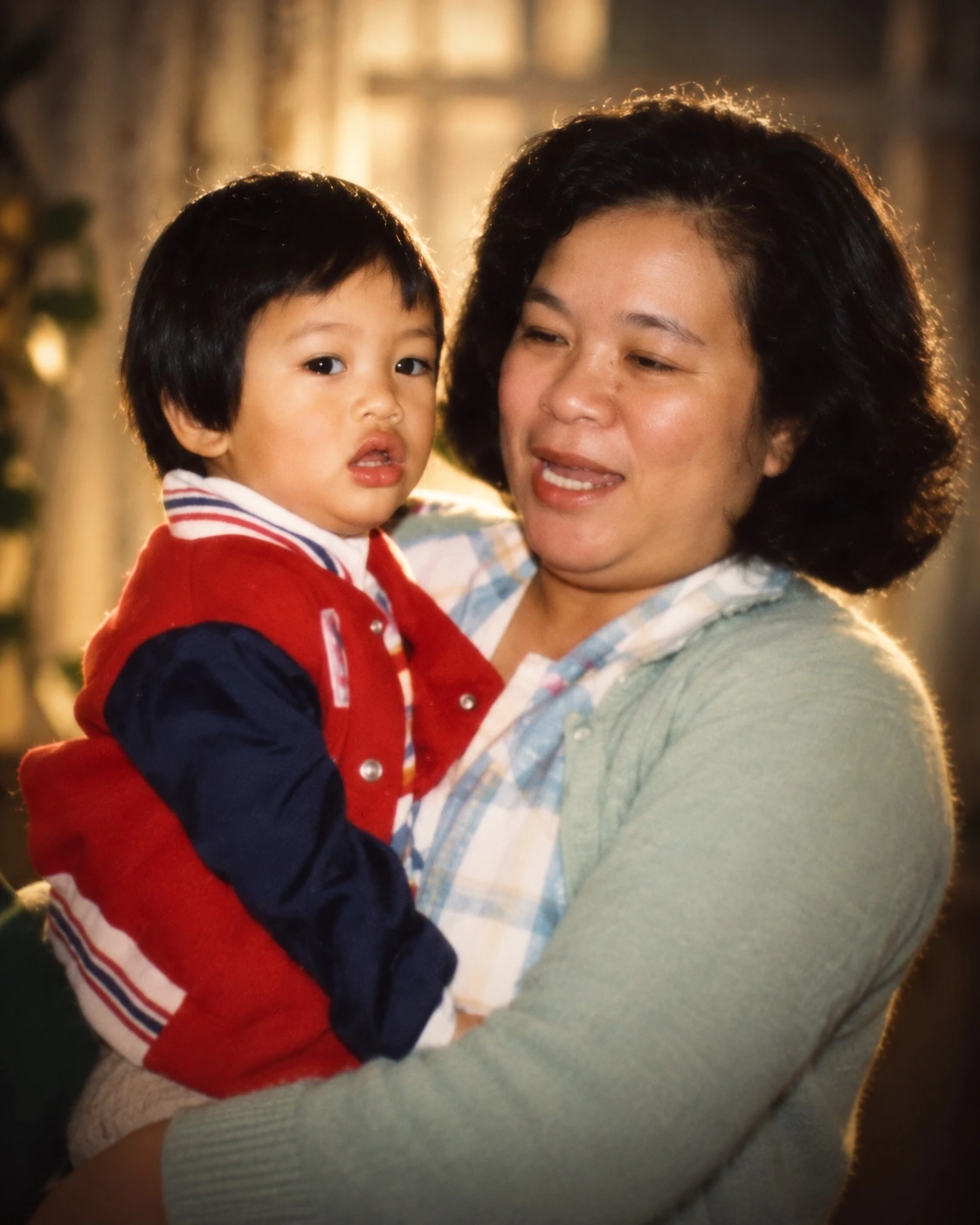 A warmly lit family photograph of a woman holding a young child.